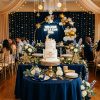Elegant celestial baby shower with navy blue linens, gold star decorations, a balloon arch, and a white tiered moon cake.