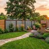 Serene backyard garden at sunset with a flagstone path, lavender, roses, and a stylish privacy fence under a warm sky.